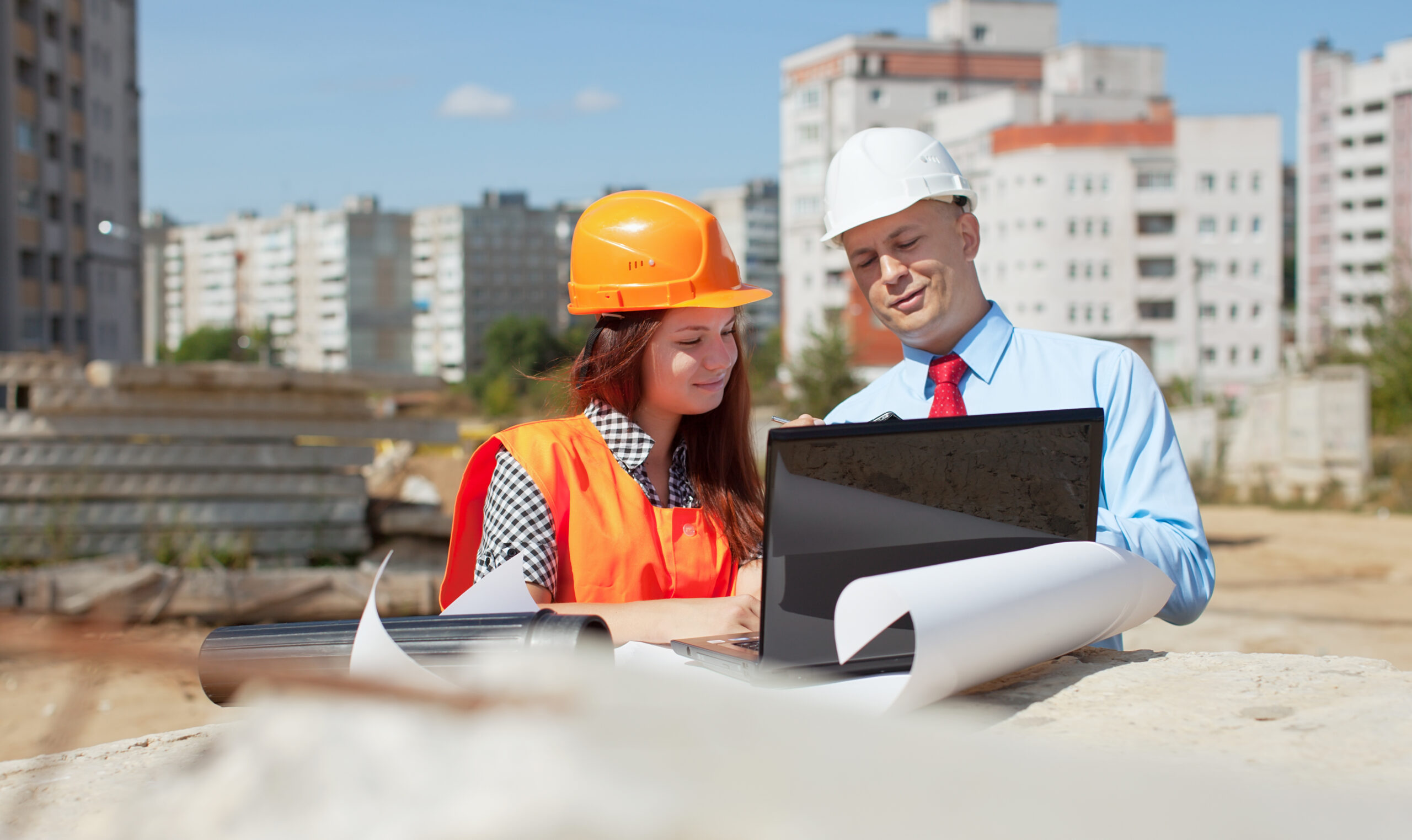 Two architects wearing protective helmet standing in front of building site